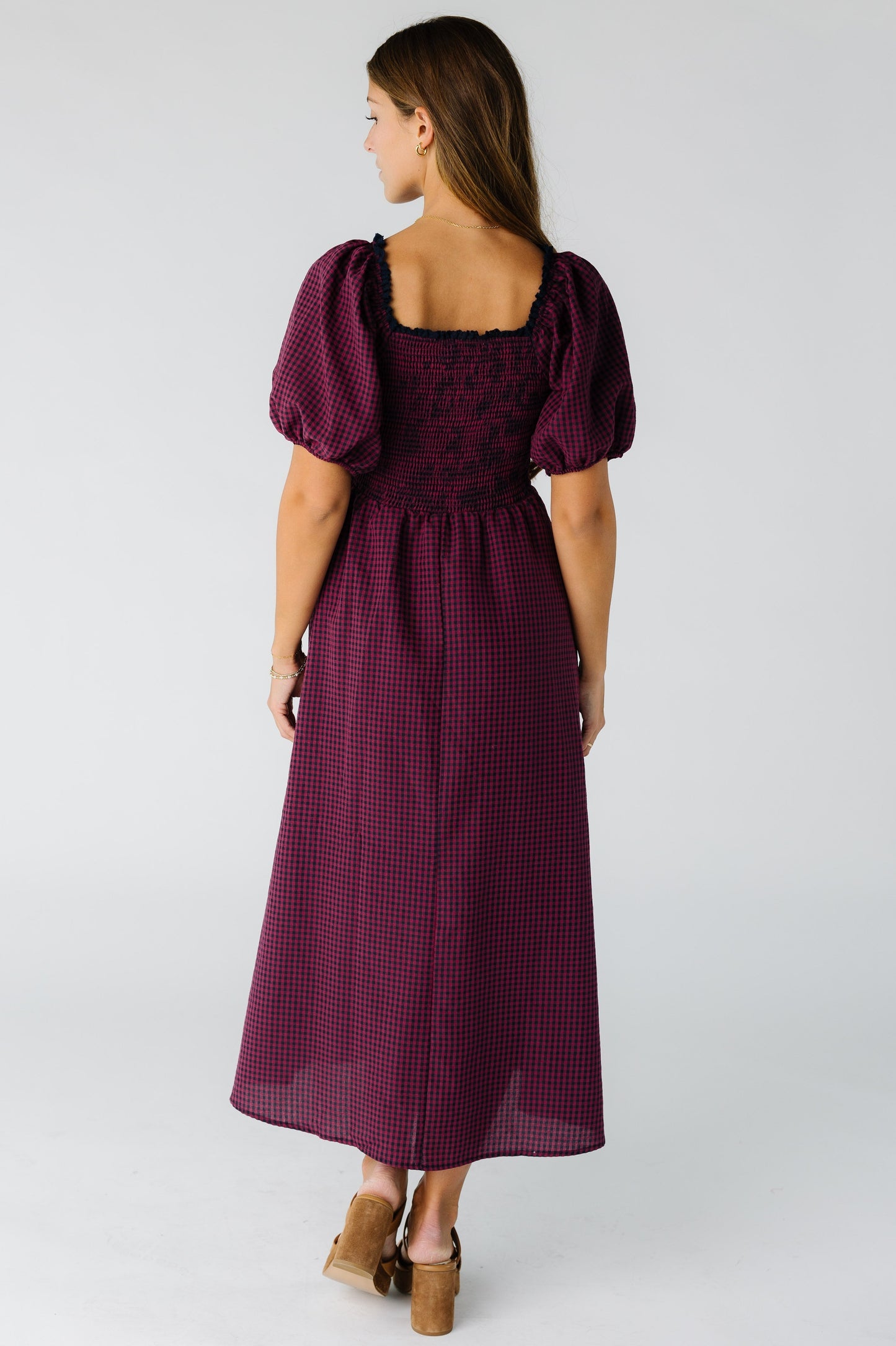 Back view of a woman wearing a burgundy midi dress with a smocked bodice and square neckline