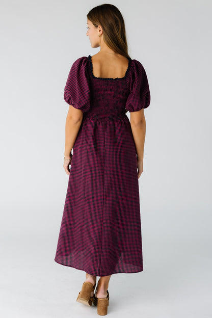 Back view of a woman wearing a burgundy midi dress with a smocked bodice and square neckline