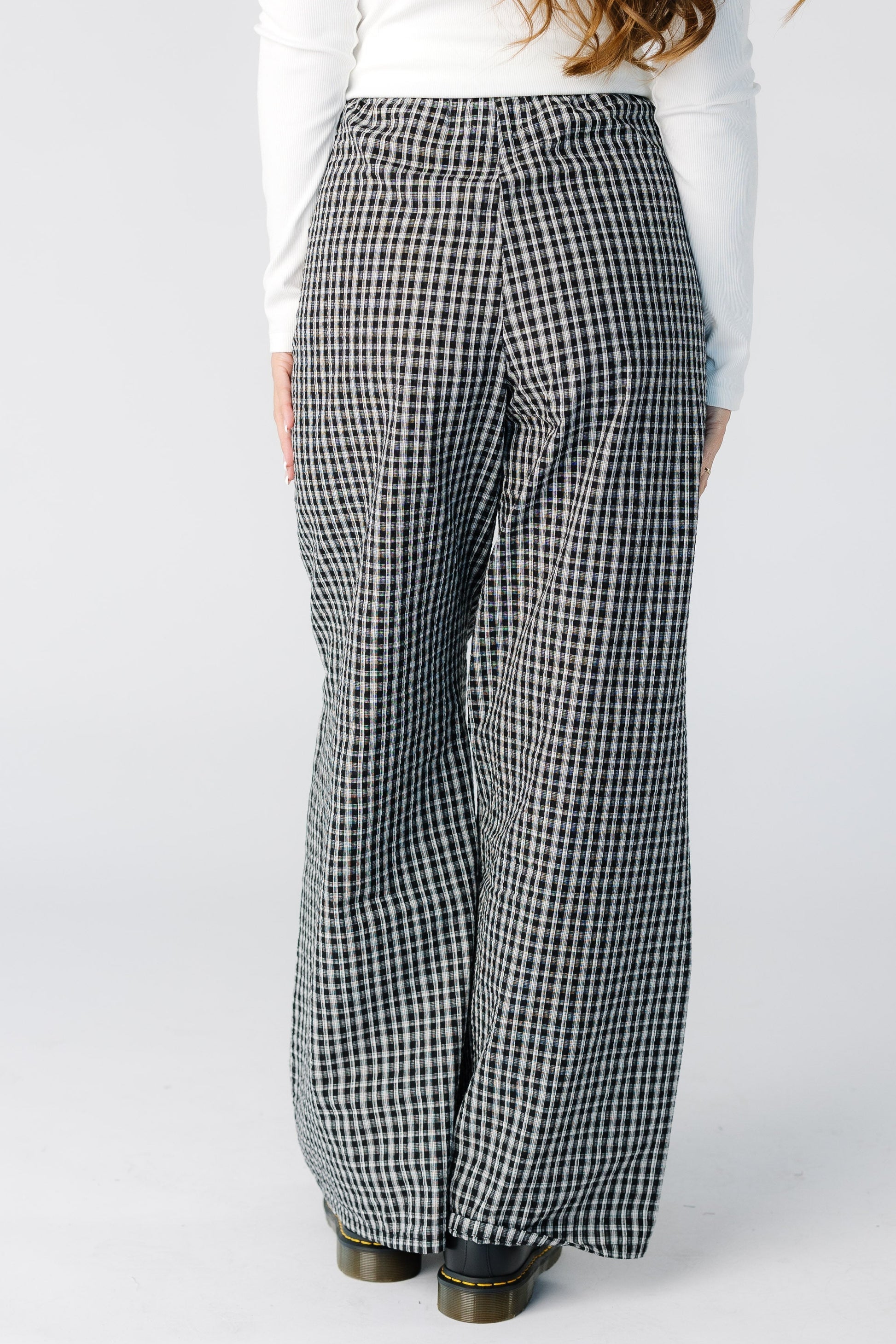 Back view of a woman wearing wide leg pant with a high rise waist in a black plaid