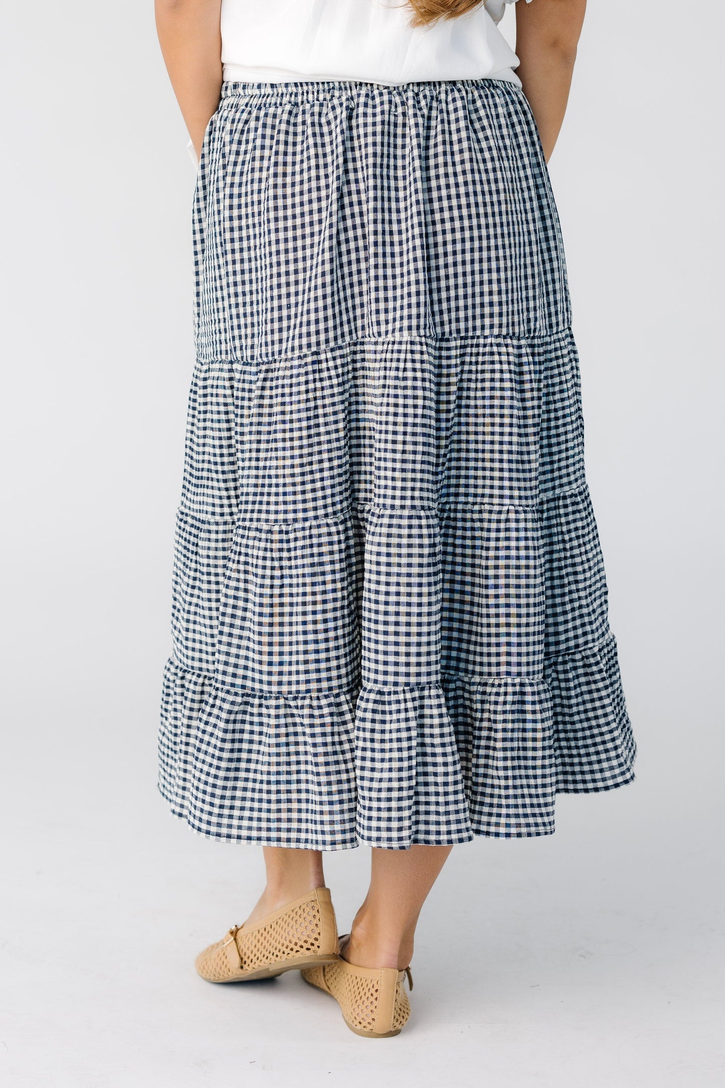 Back view of a woman wearing a navy and white gingham midi skirt