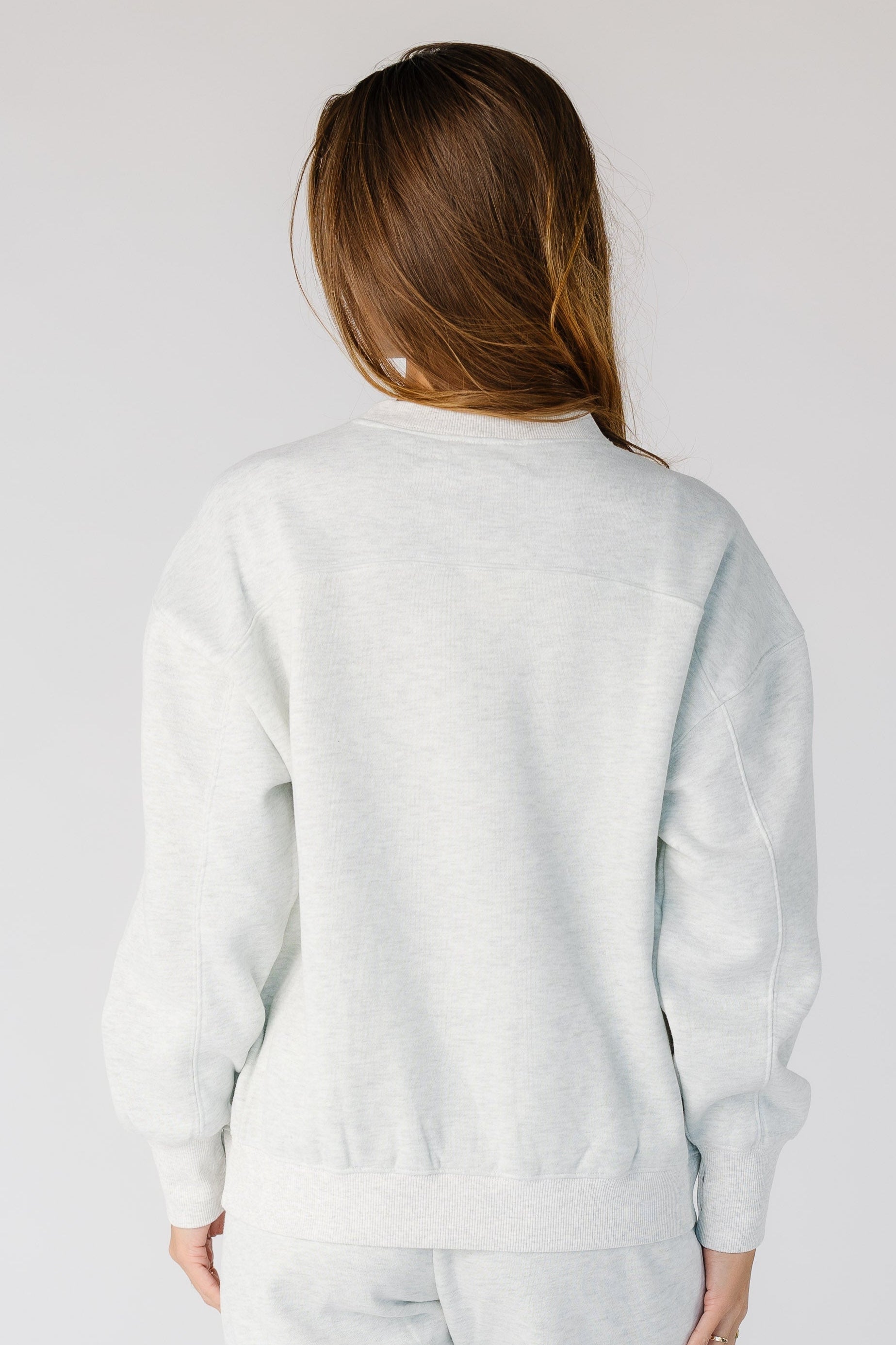 Back view of a woman wearing a light heather grey with long sleeves