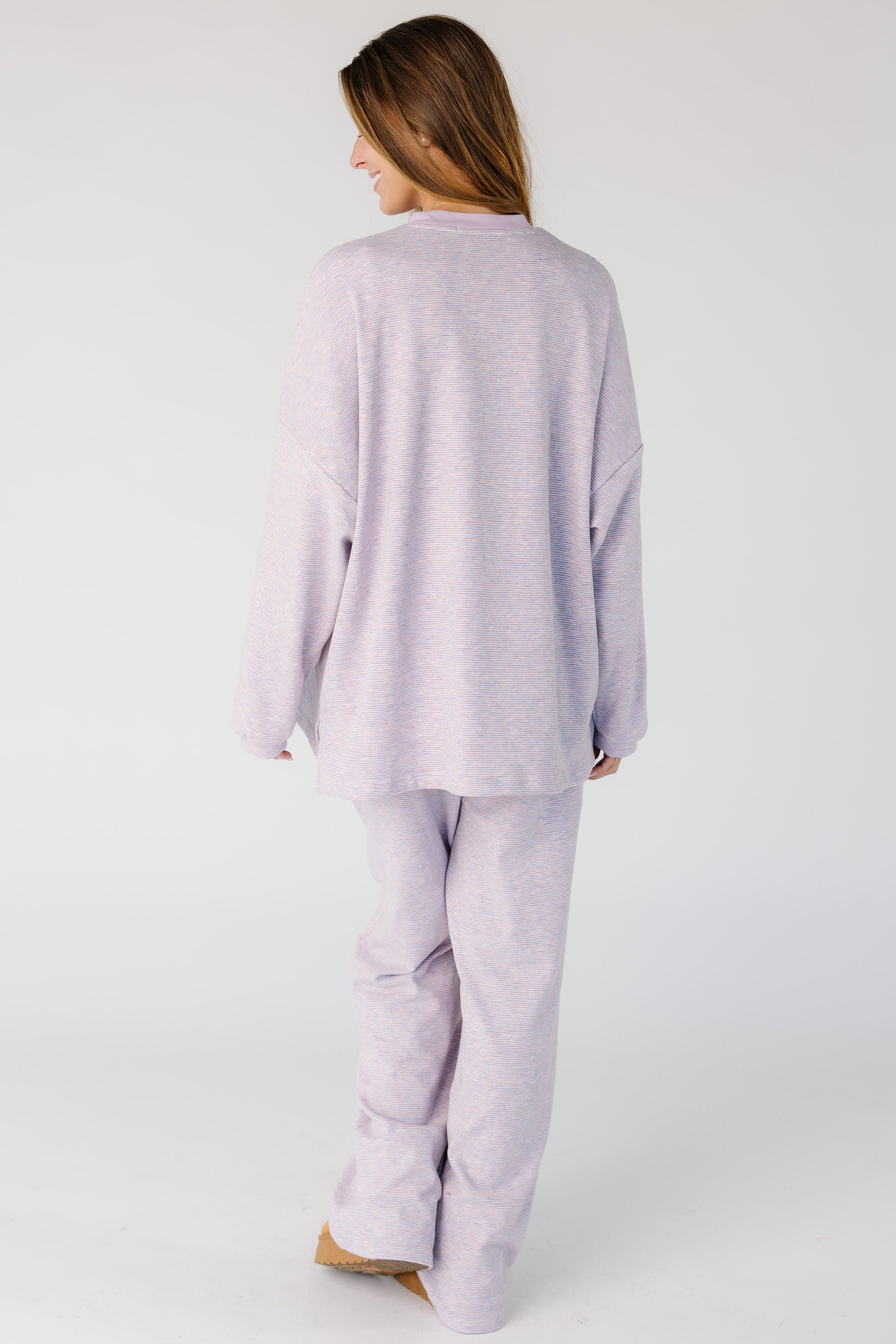 Back view of a woman wearing a lavender and pink stripe lounge set.