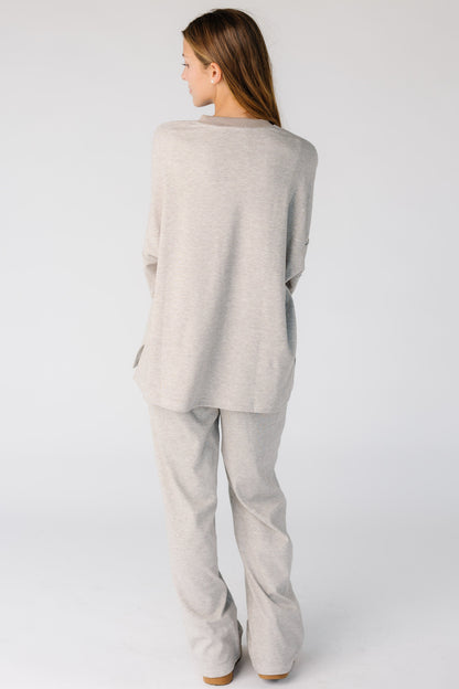 Back view of a woman wearing a taupe and white lounge set with long sleeves and long pants.