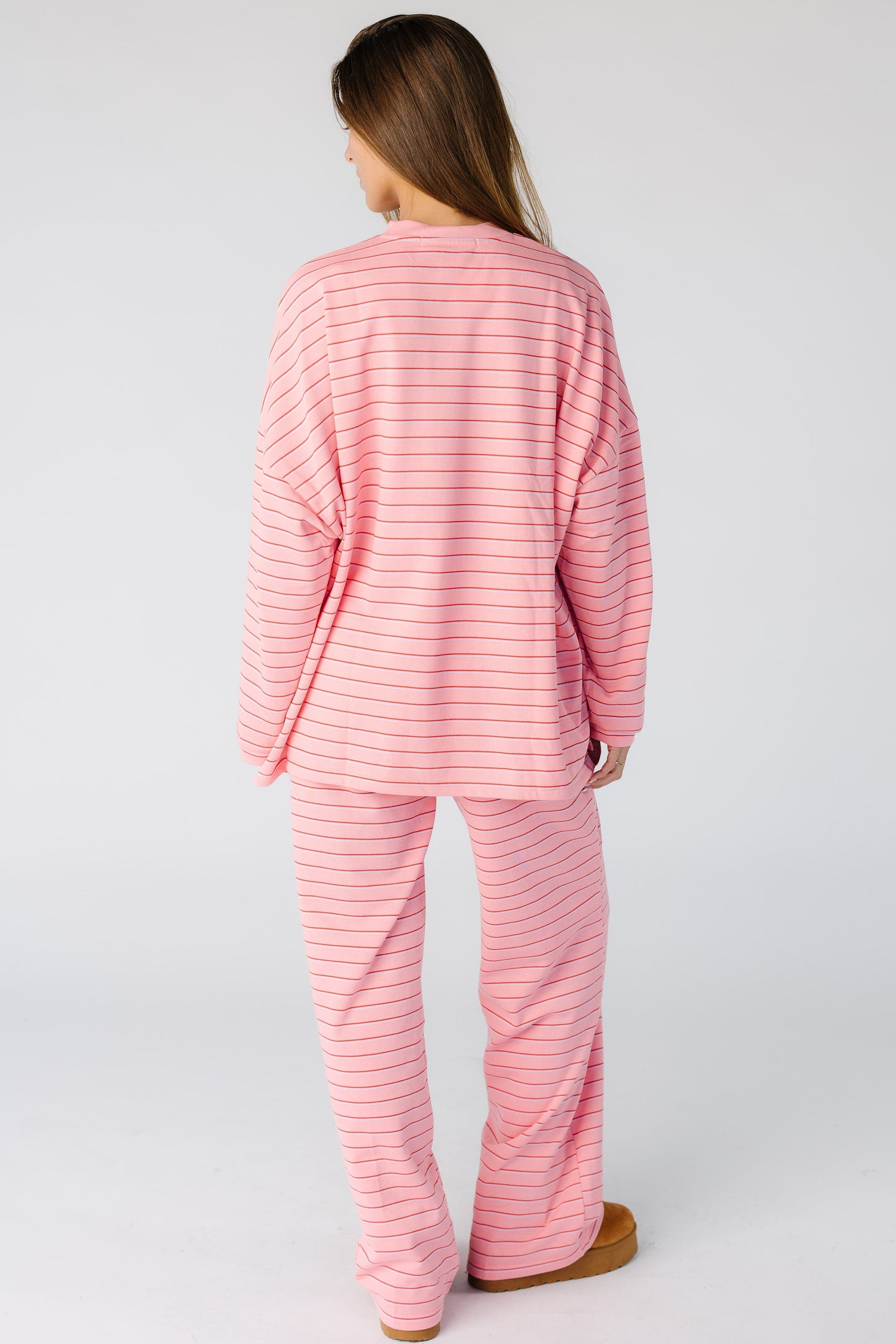 Back view of a woman wearing a loose fitting pink stripe lounge  set