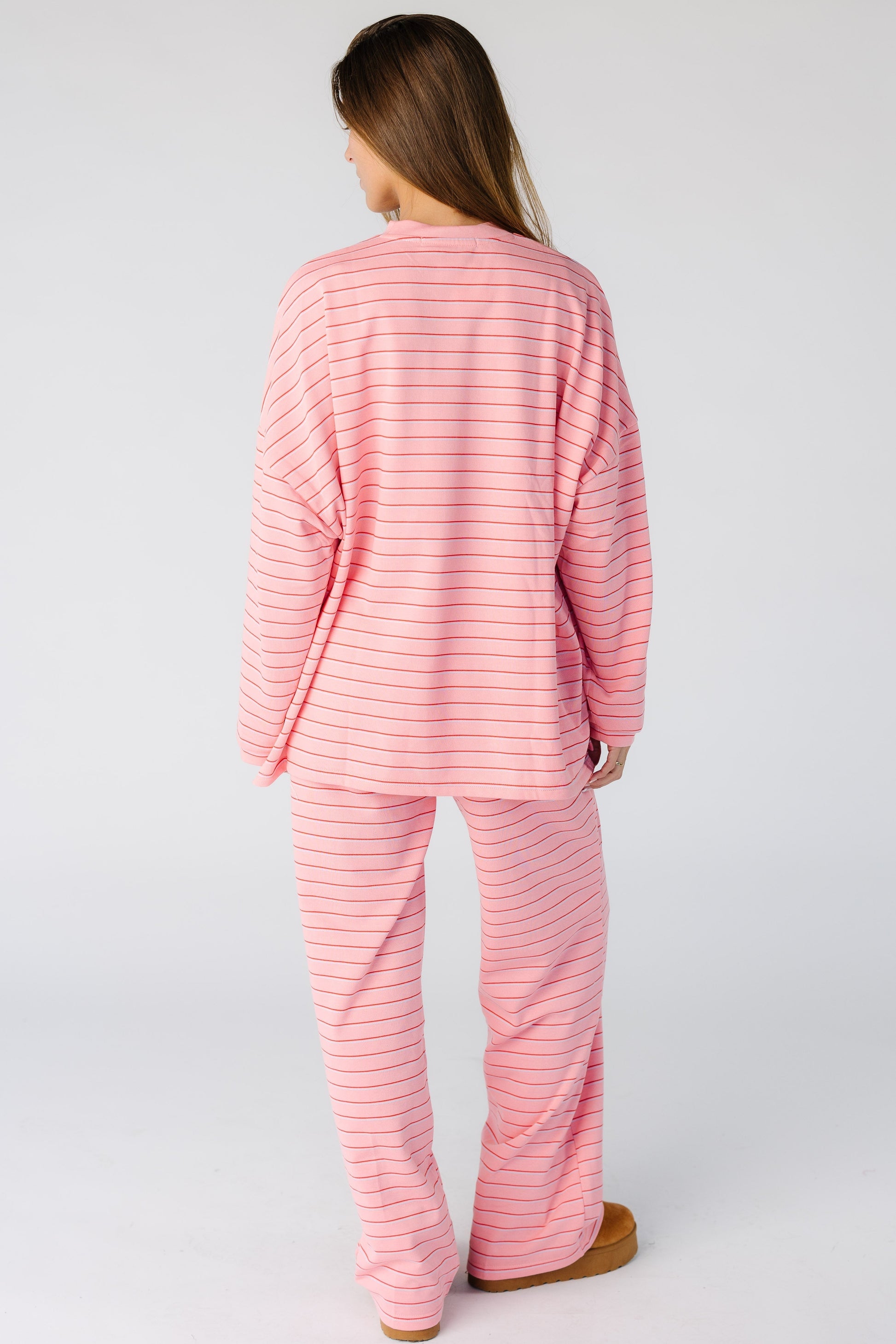 Back view of a woman wearing a loose fitting pink stripe lounge  set
