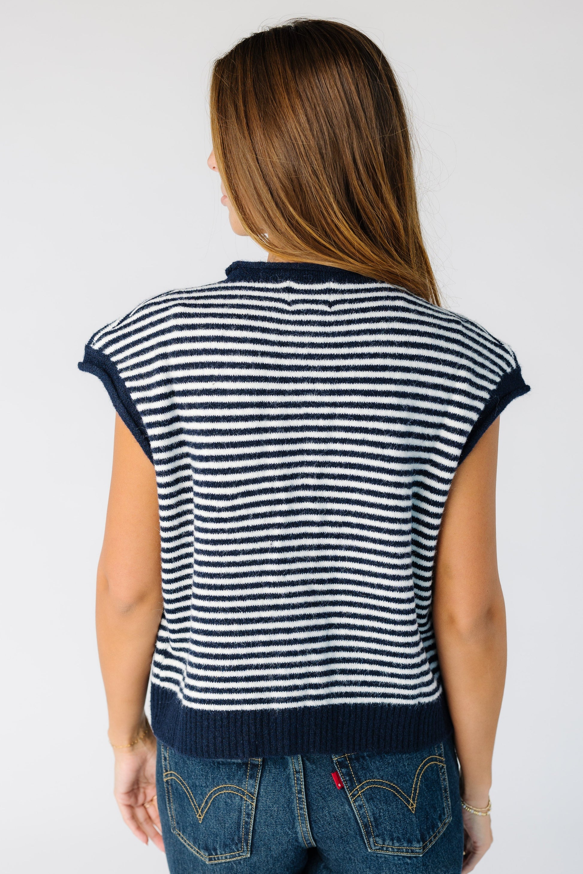Back view of a woman wearing a navy and stripe sweater vest. 