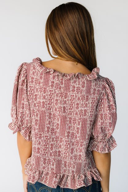 Back view of a woman wearing a loose fitting red plaid blouse with a ruffle neckline