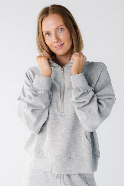 Close view of a woman wearing a heather grey lounge top with a short front zipper