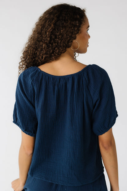Back view of a teen girl wearing a loose fitting navy top with a round neckline and short sleeves.