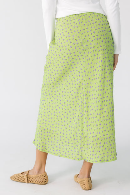 Back view of a teenage girl wearing a green floral print A-line skirt.