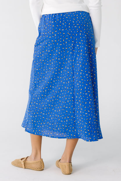 Back view of a teen girl wearing a blue floral A-line midi skirt.