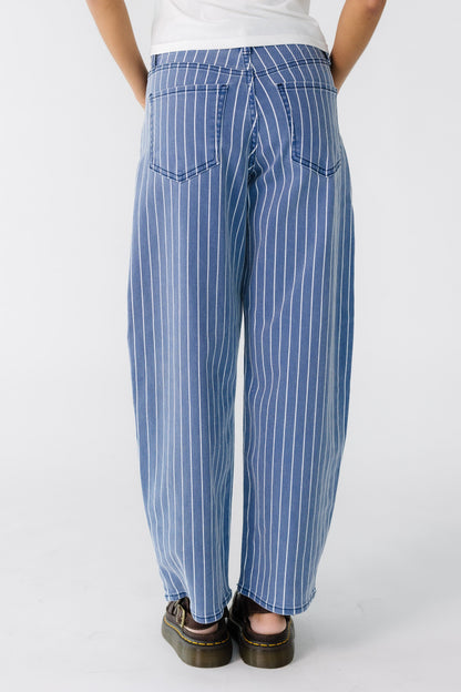 Back view of a teen girl wearing a wide leg cut pair of navy and white jeans.