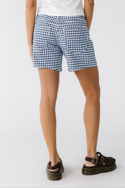 Back view of a woman wearing a pair of white and navy gingham shorts.