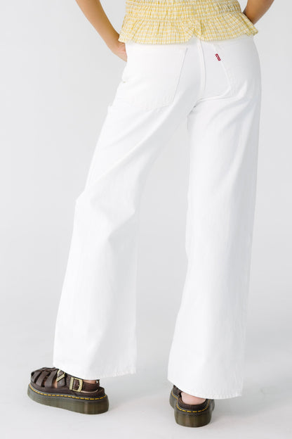 Back view of a woman wearing white Levi's jeans with a wide cut leg.
