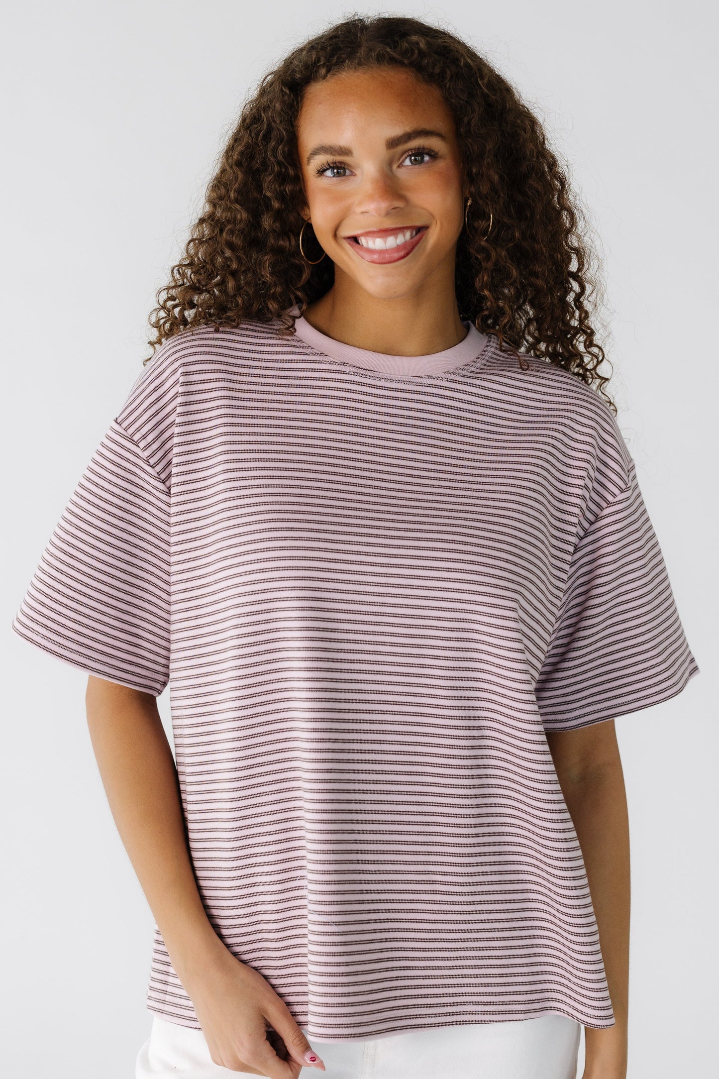 Teen girl wearing a pink and brown stripe modest tee with a crew neckline and short sleeves.
