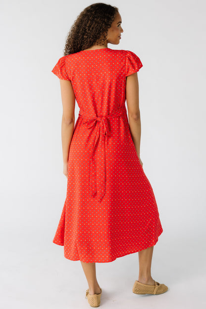 Back view of a teen girl wearing a red floral midi dress with short flutter sleeves and a back tie.