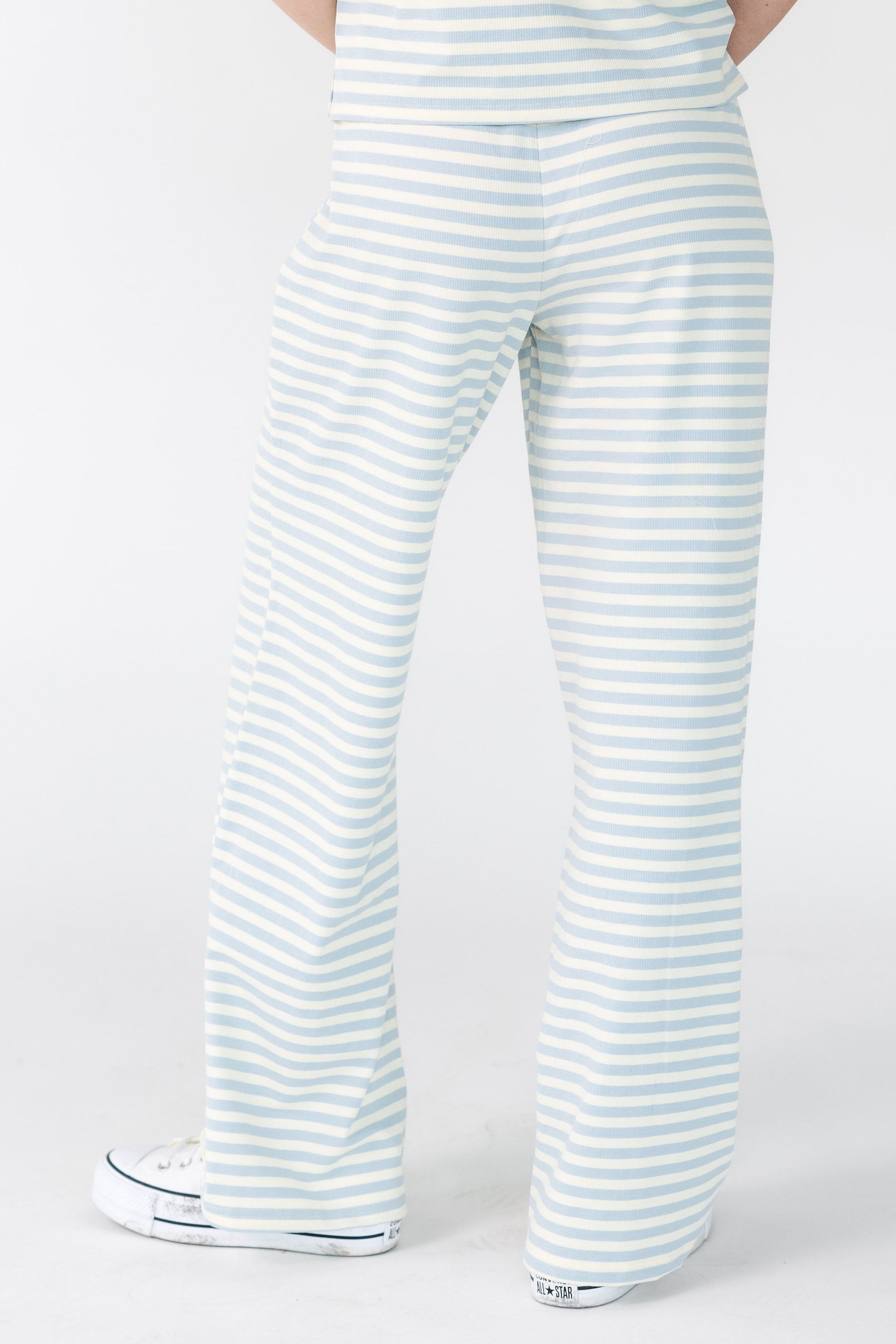 Back view of a young woman wearing a light blue and white stripe lounge pant.