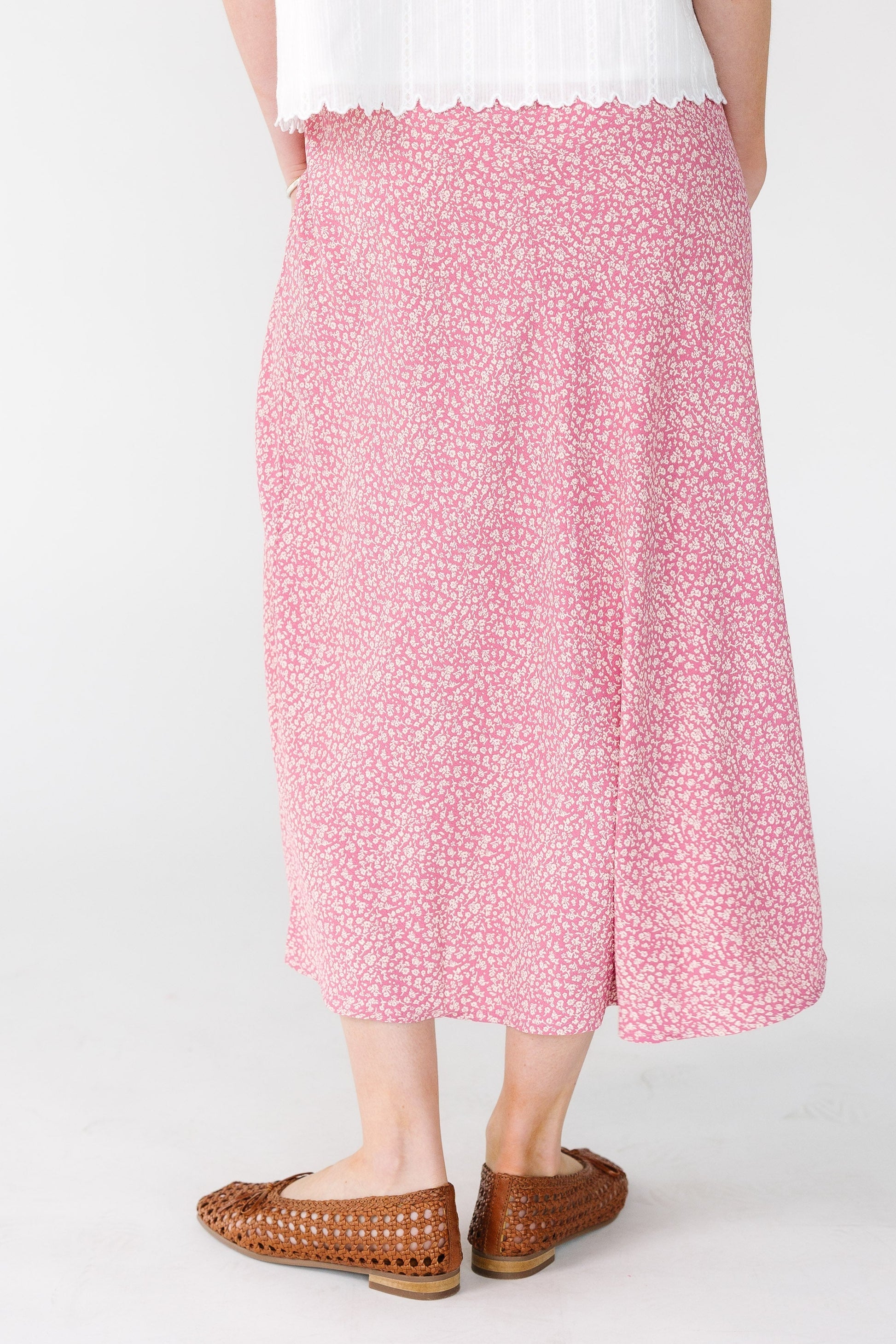 Back view of a woman wearing a pink and white A-line midi skirt.