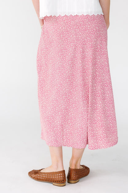 Back view of a woman wearing a pink and white A-line midi skirt.