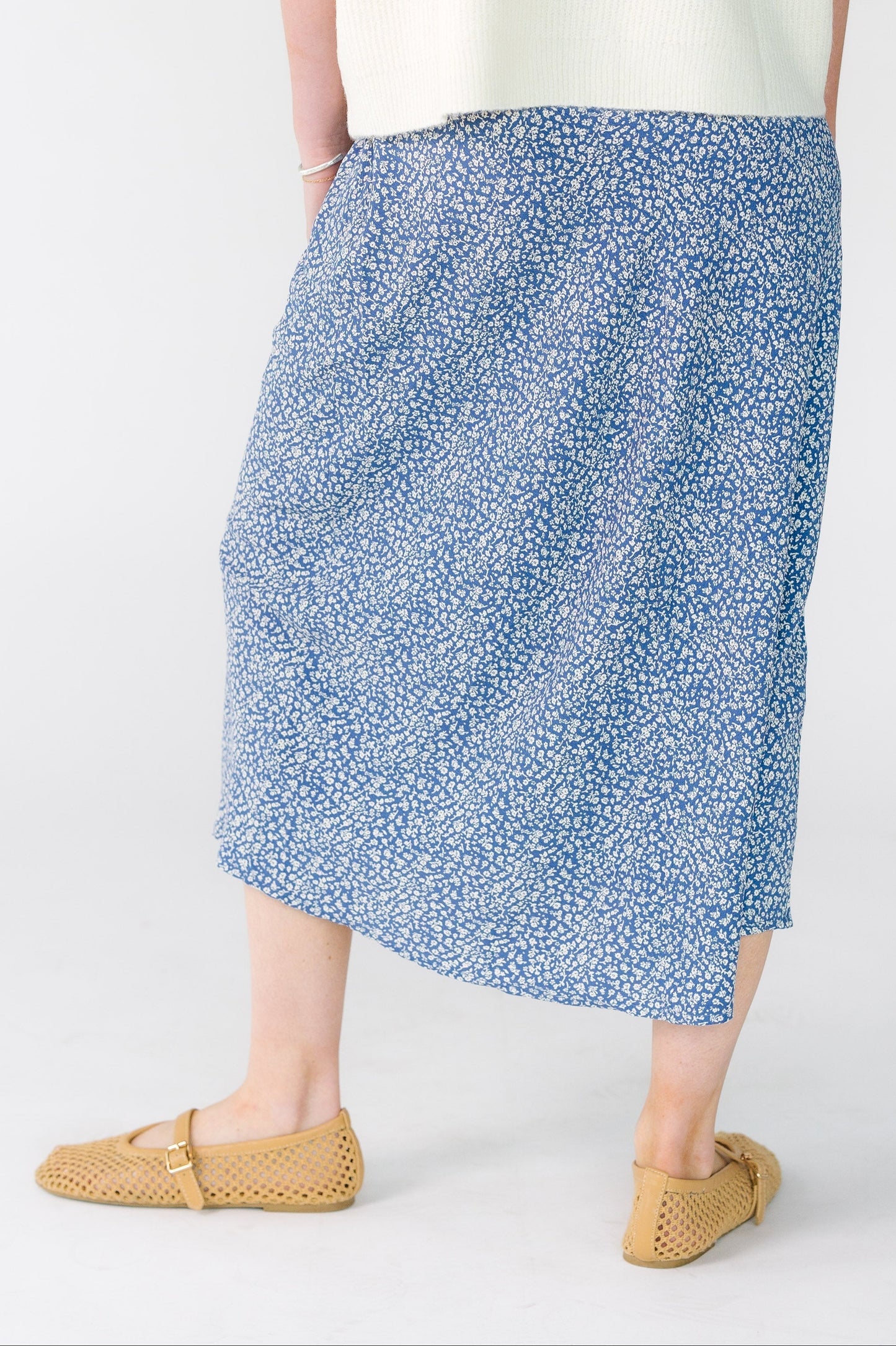 Back view of a woman wearing an A-line midi skirt in navy with white floral print.