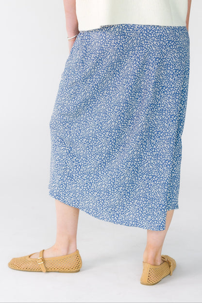 Back view of a woman wearing an A-line midi skirt in navy with white floral print.