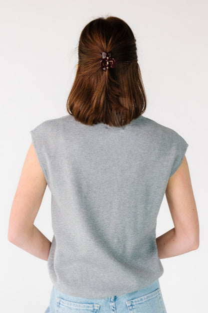 Back view of a woman wearing a grey loose loose fitting sweater vest.