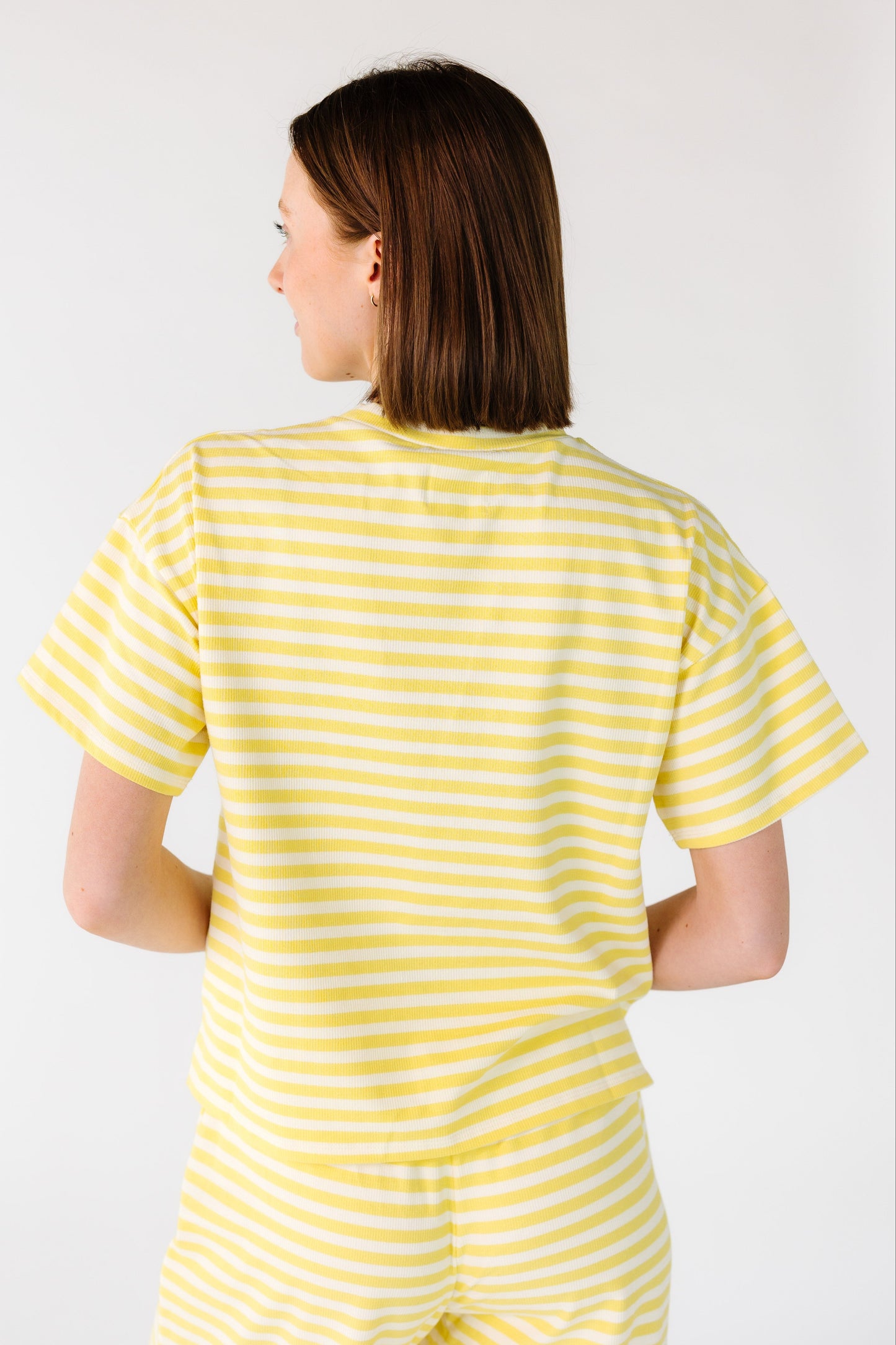 Back view of a woman wearing a  yellow and white stripe tee with short sleeves.