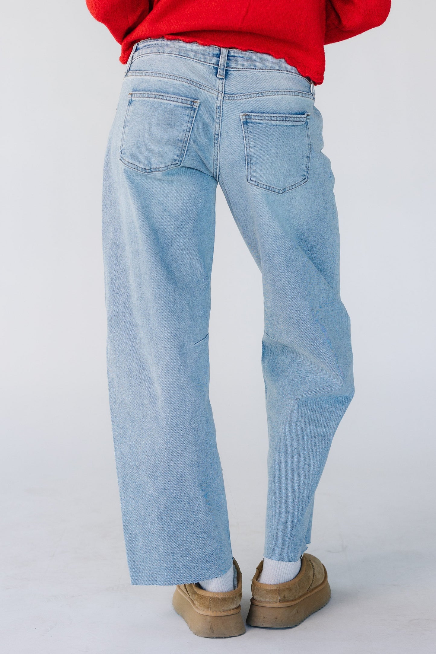 Back view of a woman wearing a pair of light denim barrel jeans.