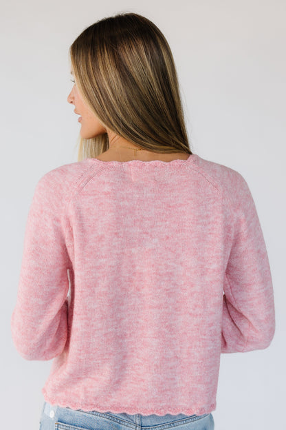 Back view of a woman wearing a light pink cardigan with long sleeves.