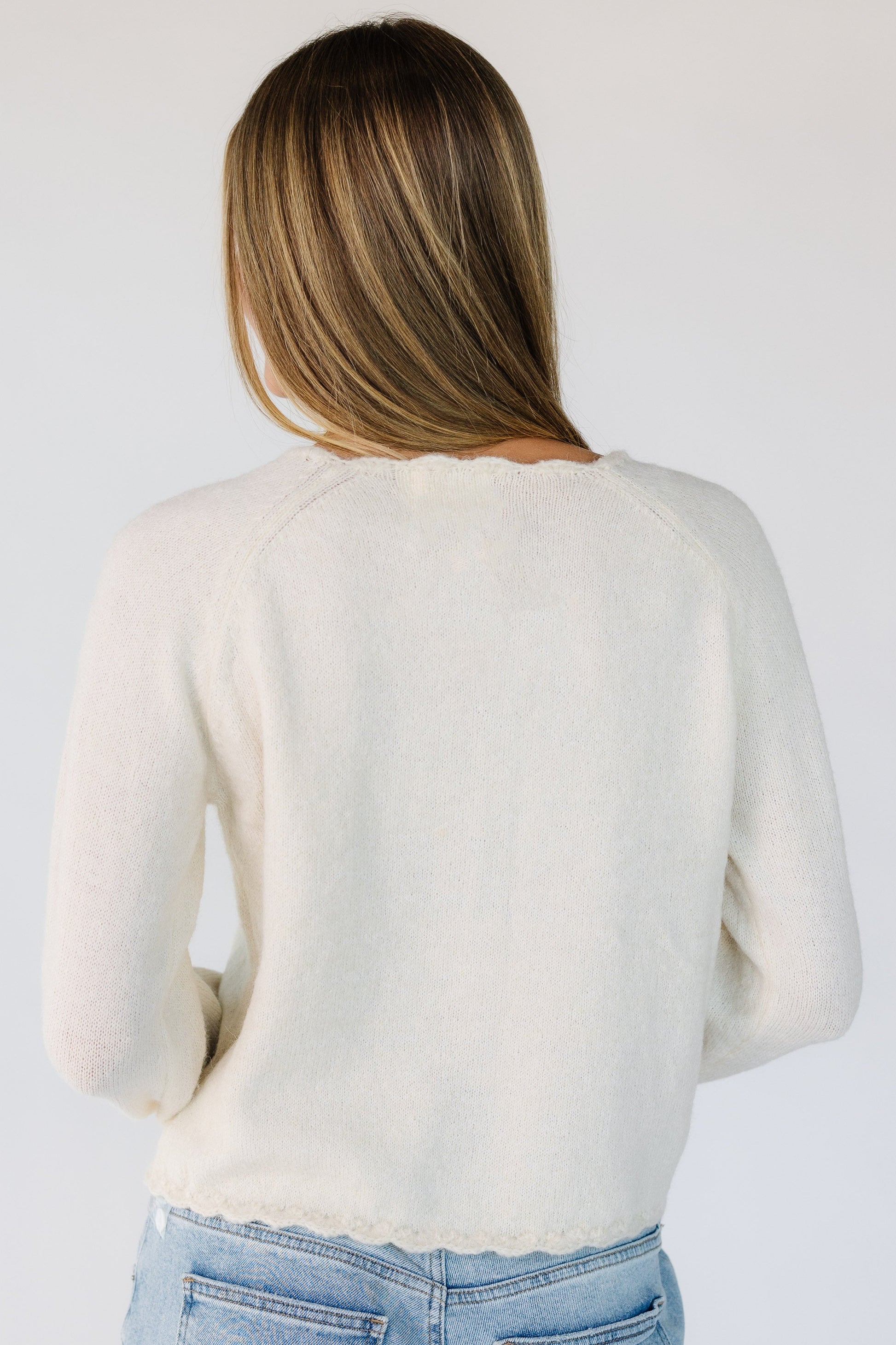 Back view of a woman wearing a cream long sleeve cardigan.