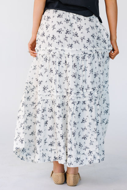 Back view of a woman wearing a white and black floral print midi skirt.