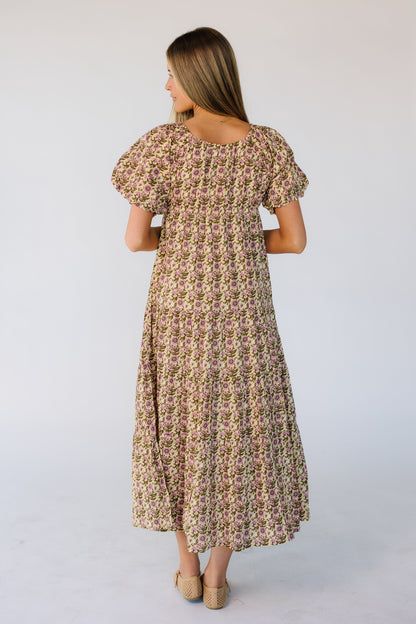 Back view of a woman wearing a green & pink floral print midi dress with large puff sleeves.