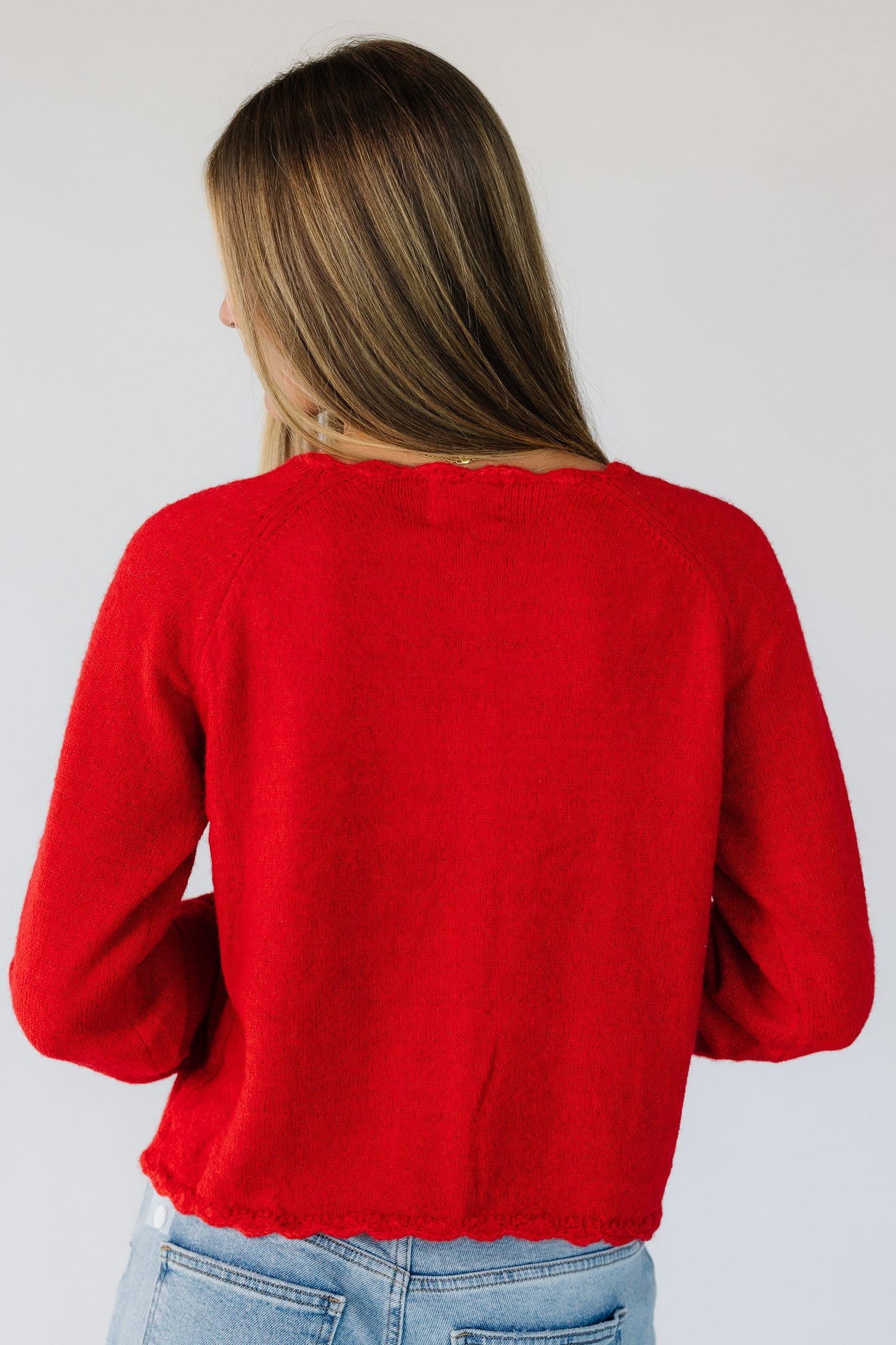 Back view of a woman wearing a red cardigan with long sleeves.