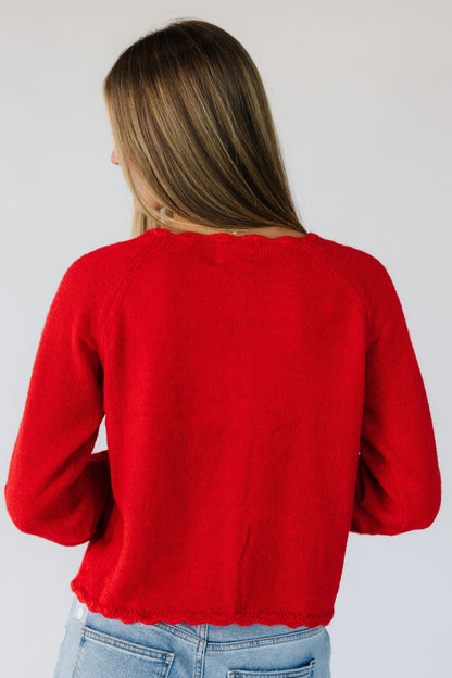 Back view of a woman wearing a red cardigan with long sleeves.