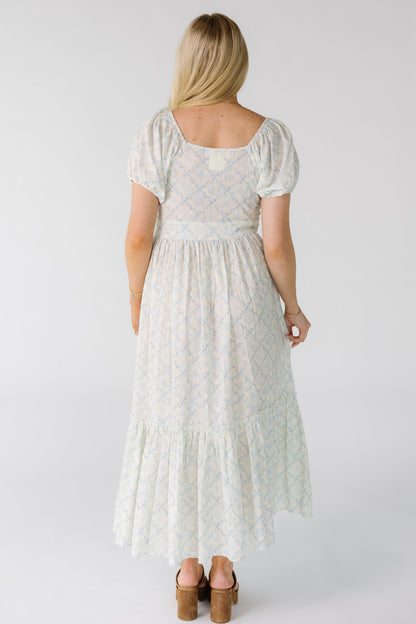 Back view of a woman wearing a white floral midi dress with square back neckline with short puff sleeves.