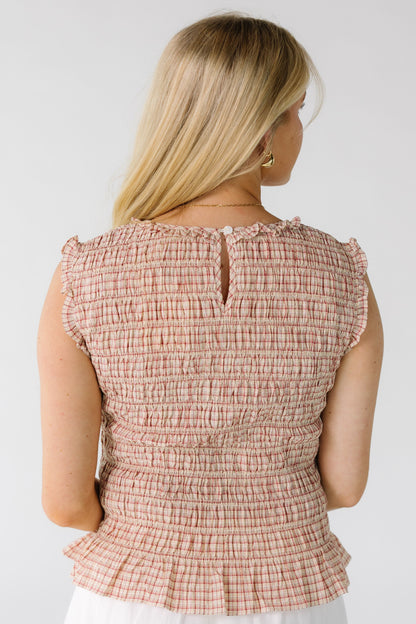 Back view of a woman wearing a red plaid smocked bodice top with a button-keyhole closure.