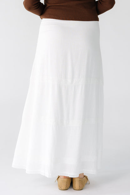 Back view of a woman wearing a white A-line midi skirt with a lace hem.