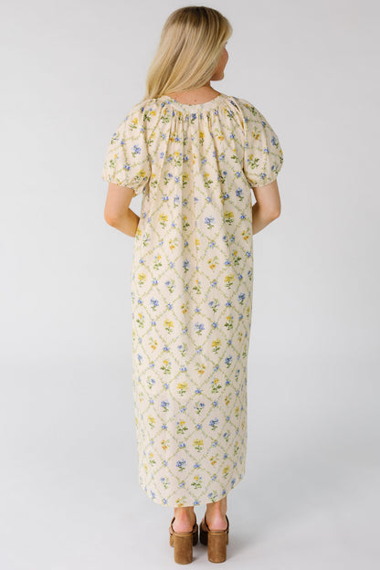 Back view of woman wearing a loose fitting midi dress with a gathered neckline and short balloon sleeves.