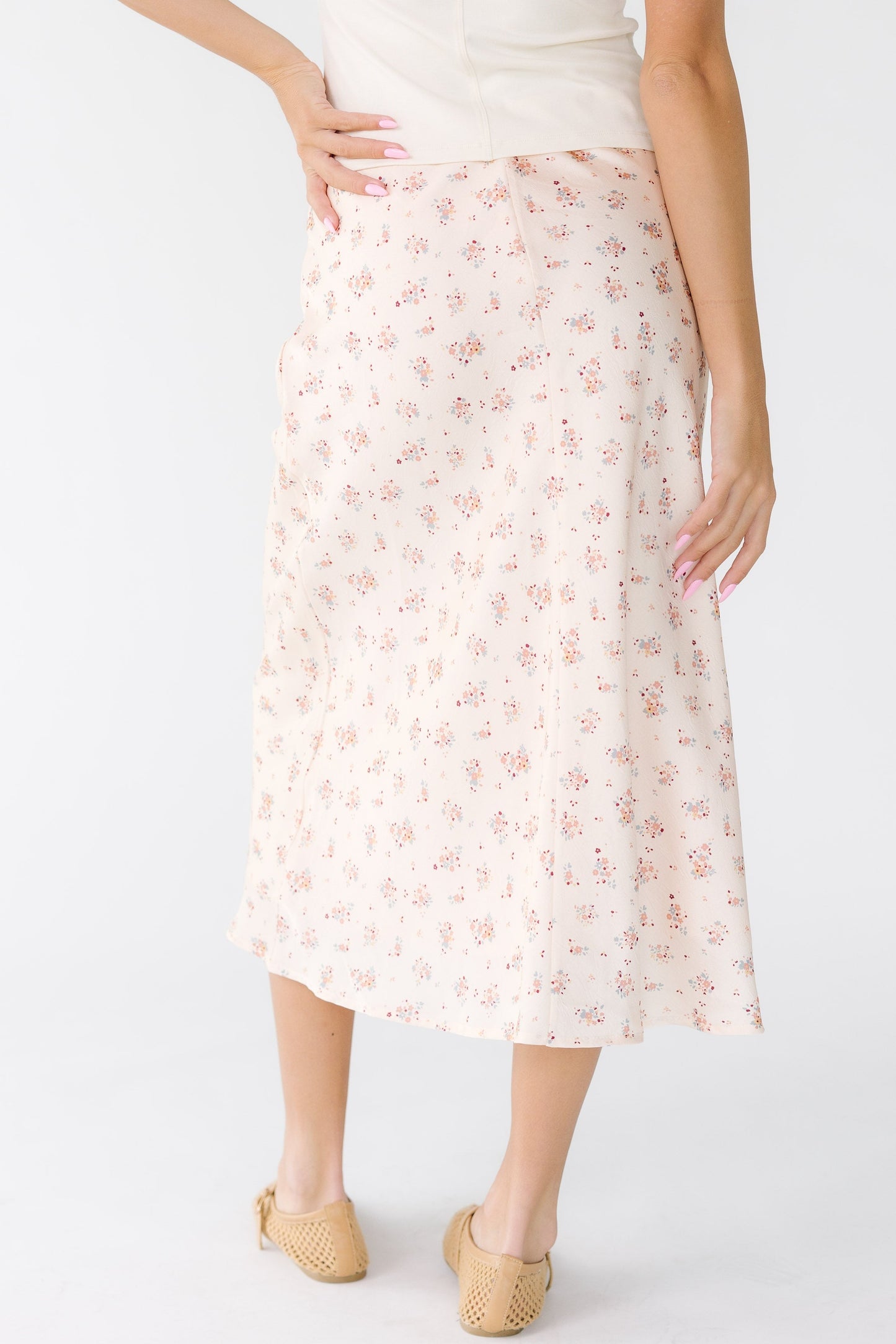 Back view of a woman wearing an ivory and pink floral A-line skirt.