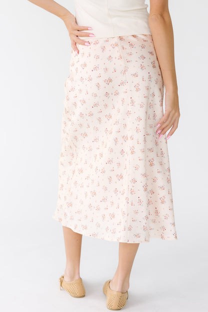 Back view of a woman wearing an ivory and pink floral A-line skirt.