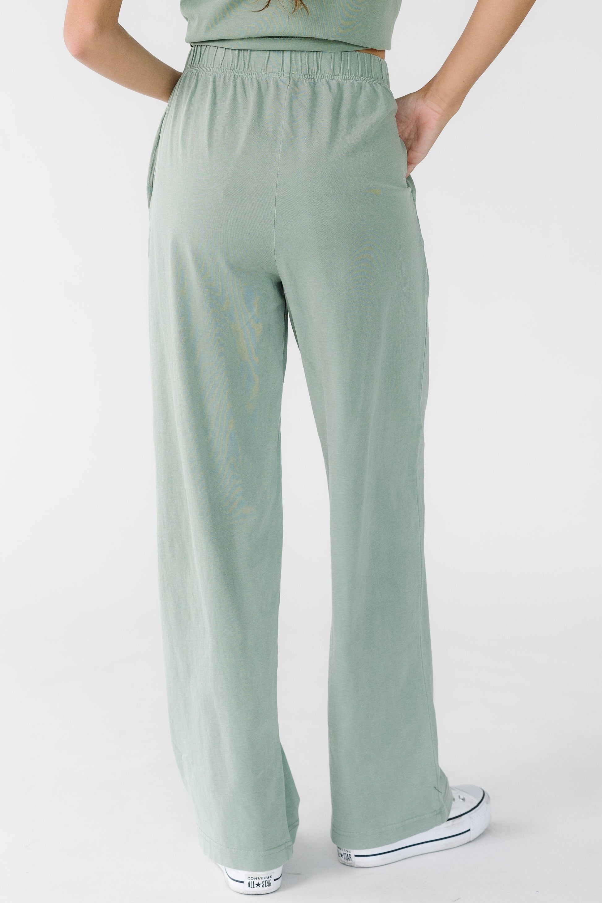 Back view of a woman wearing a pair of loose fitting pants with an elastic waistband.