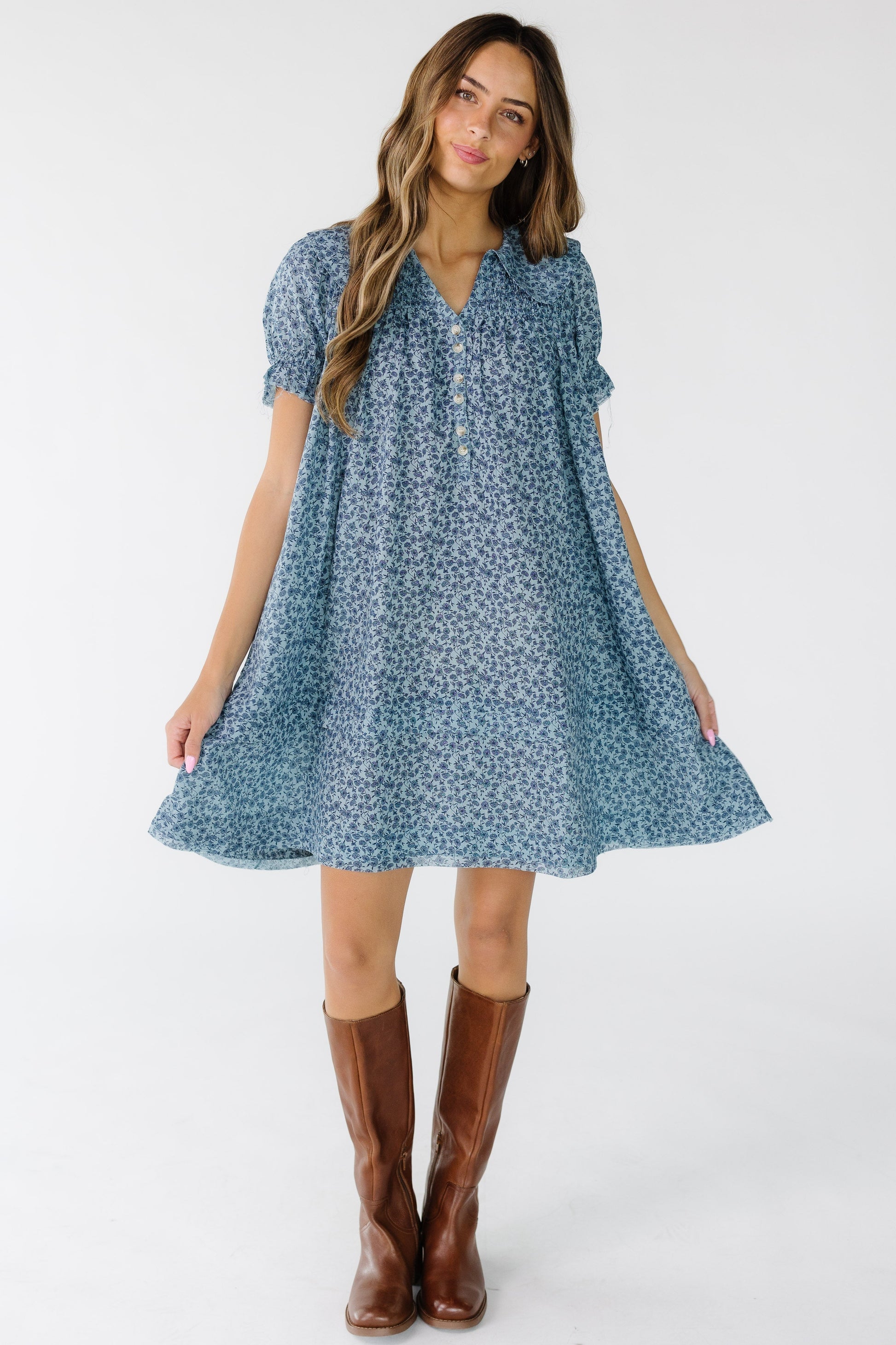 Woman wearing a blue floral print above knee dress that is loose fitting and has short sleeves.