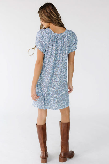 Woman wearing a blue floral print, above knee dress with short sleeves.