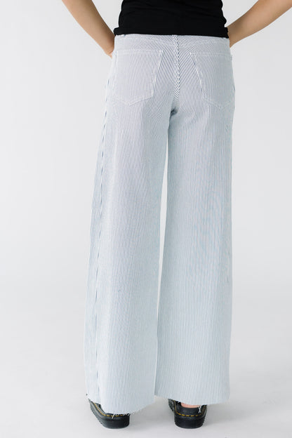 Back view of a woman wearing white wide leg jeans with thin navy stripes.