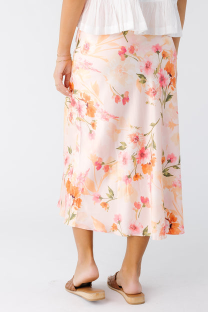 Back view of a young woman wearing a pink floral A-line midi skirt.
