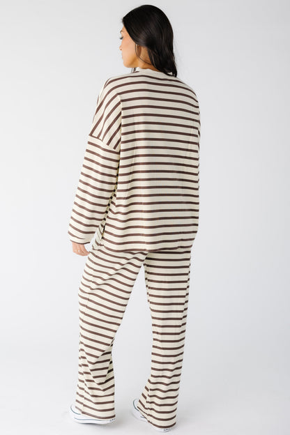 Back view of a woman wearing a loose fitting cream and brown stripe lounge set.