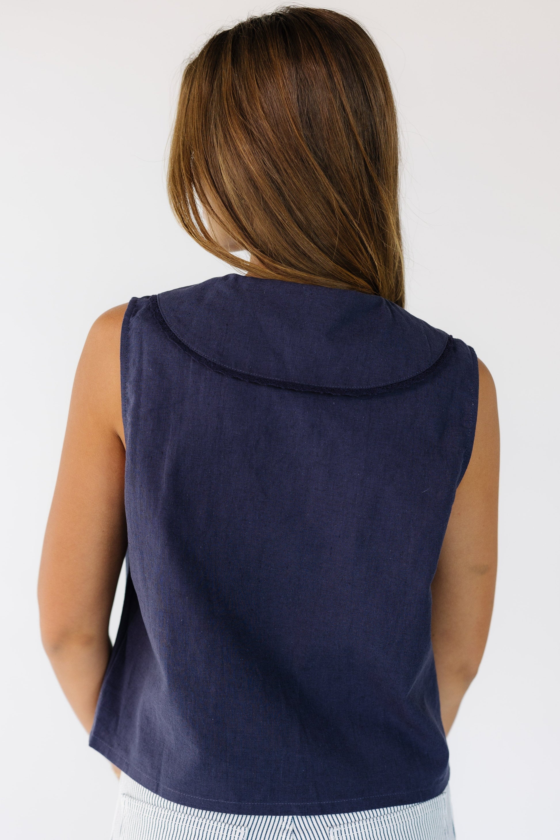 Young woman wearing a navy loose fitting top with a lace edge collar.