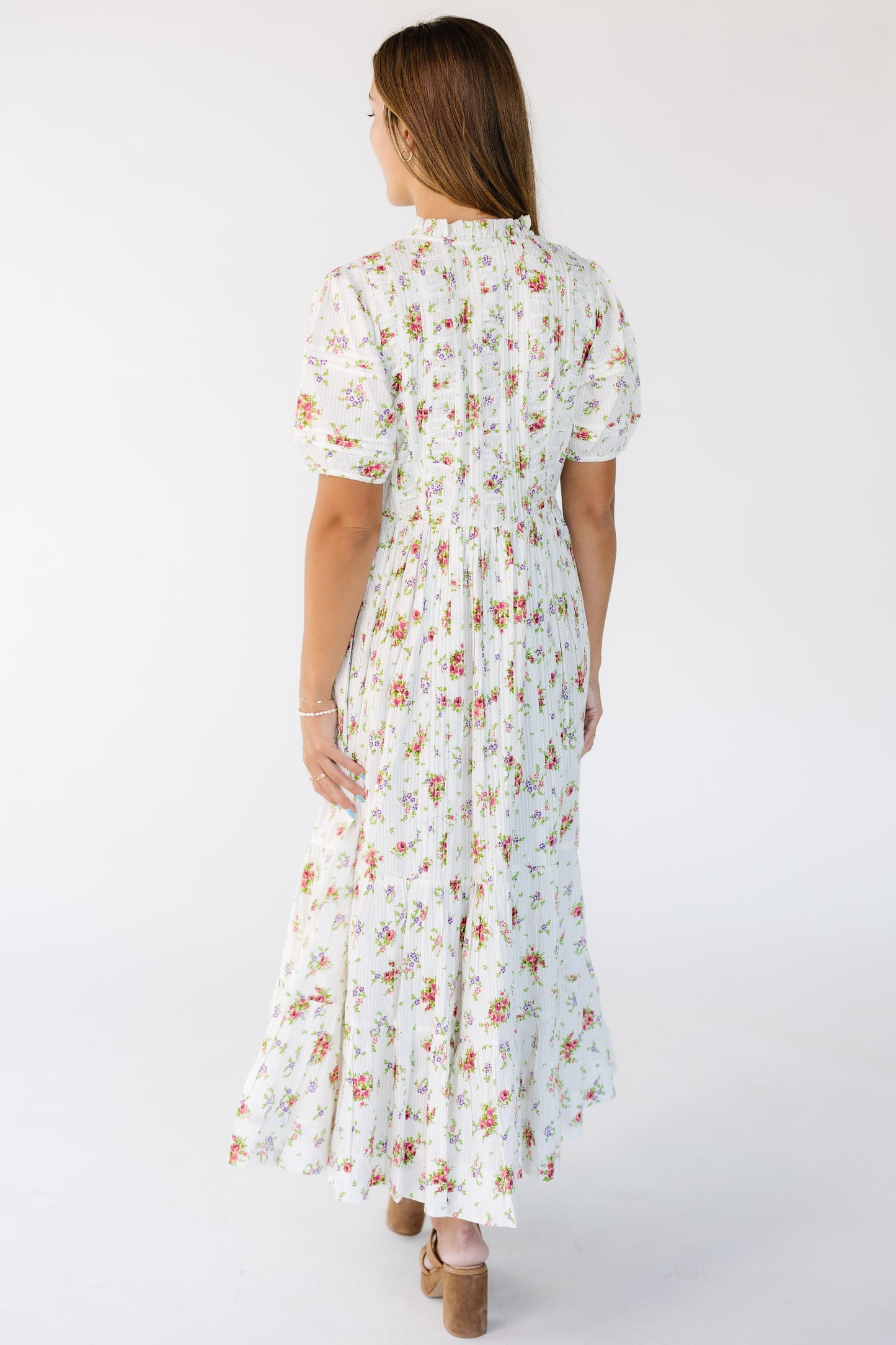 Back view of a woman wearing a loose fitting white floral print midi-maxi dress.