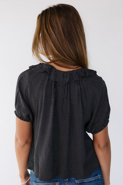 Back view of a young woman wearing a black with white polka dots and short puff sleeves.