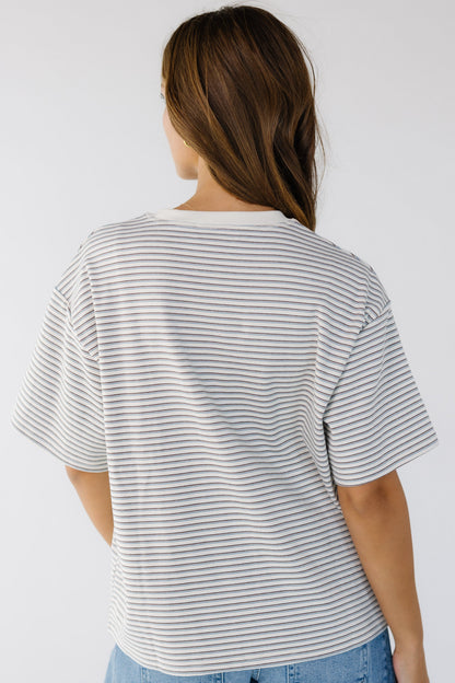 Back view of a woman wearing a loose fitting stripe tee with short sleeves with a crew neckline.